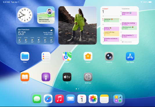 Três modelos de iPad, colocados na horizontal, com o modelo central sobreposto aos outros dois. O modelo central tem um Apple Pencil encaixado de forma magnética na sua parte superior. O ecrã central mostra o ecrã principal com ícones de apps coloridos com efeito Liquid Glass; o ecrã à esquerda mostra a app Pré-visualização; o ecrã à direita mostra o ecrã principal com ficheiros a expandirem verticalmente a partir da Dock