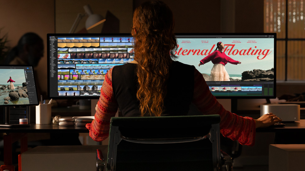 Vista posterior de una persona sentada frente a dos monitores que muestran contenido de un vídeo que se está editando.