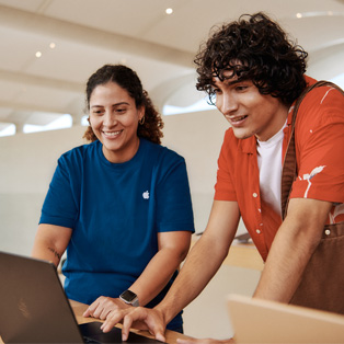 Una dipendente dell’Apple Store in piedi accanto a un cliente, entrambi interagiscono con un MacBook.