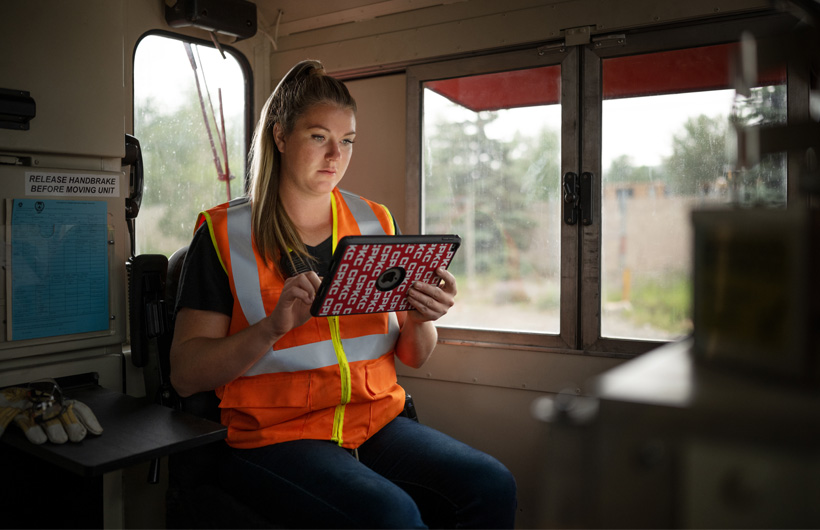 Une cheminote assise dans un wagon à l’arrêt consulte un iPad