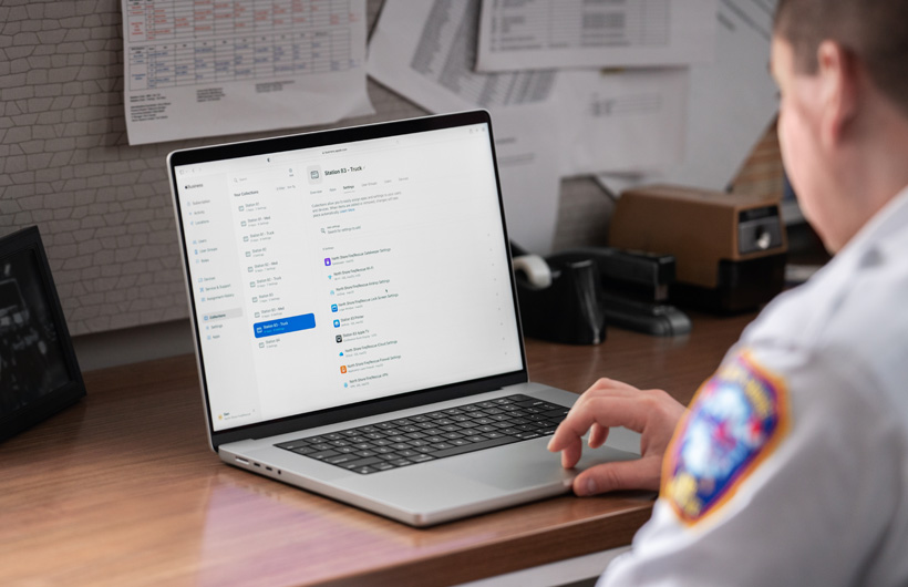 Un membre de la direction du service d’incendie installé à un bureau utilise un MacBook avec Apple Business Essentials ouvert à l’écran