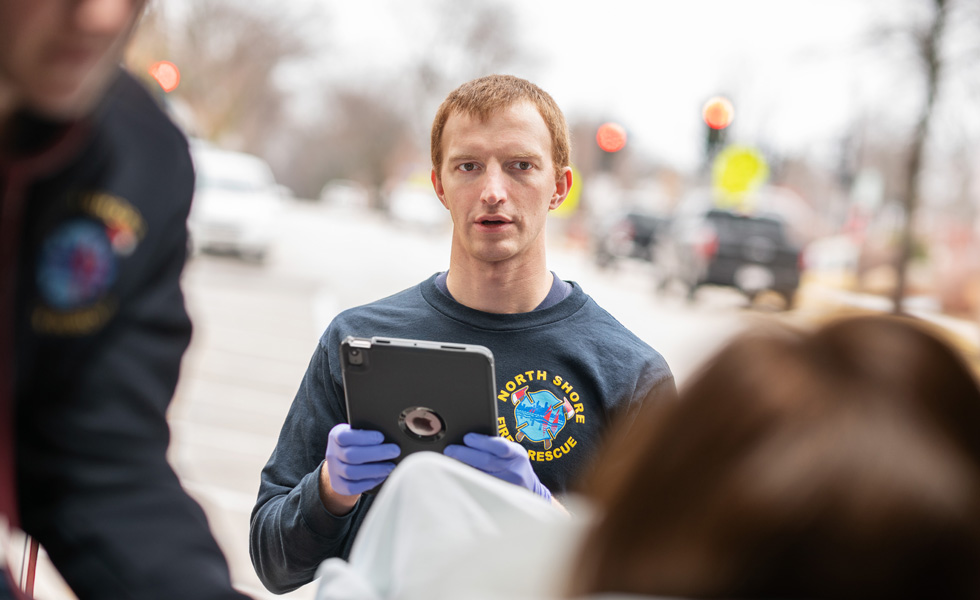 Un membre de l’équipe tenant un iPad parle à une personne se trouvant dans une ambulance.