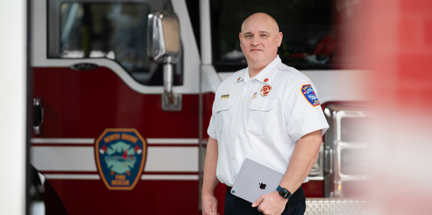 Le chef du service d’incendie devant un camion de pompiers, un iPad à la main et une Apple Watch au poignet